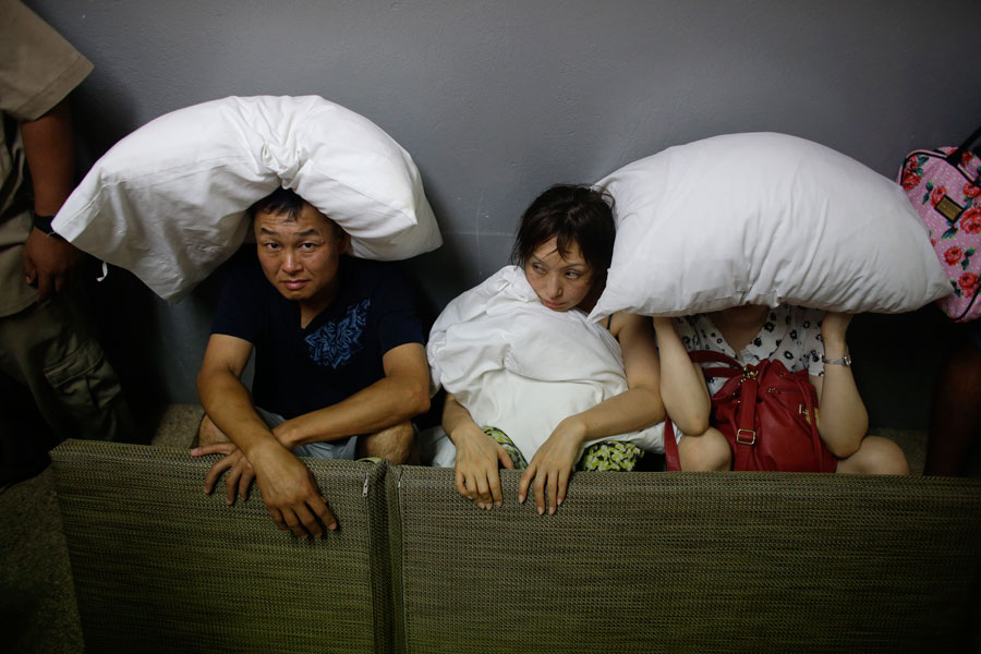 A family from San Jose, California, cover themselves with pillows as they sit on the concrete stairs in the service area of a resort after the designated area for shelter was destroyed by winds in Los Cabos, Mexico, Monday, Sept. 15, 2014. Hurricane Odile raked the Baja California Peninsula with strong winds and heavy rains early Monday as locals and tourists in the resort area of Los Cabos began to emerge from shelters and assess the damage. (AP Photo/Victor R. Caivano)